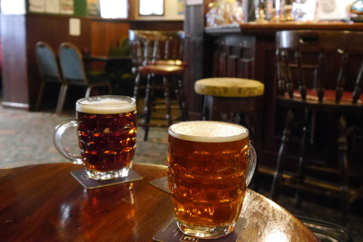 Pints of beer on a wooden table in a traditional pub.